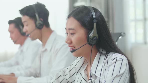 Close Up Of Three Asian Call Centre Agents Typing On Computer While Speaking To Customers alt