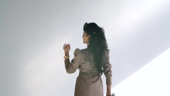 Glamorous Woman Posing and Spinning in a White Room in the Rays of Daylight. A Hot Brunette in a alt