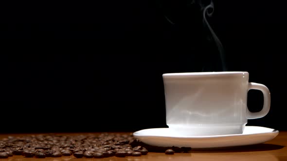 White, Hot Coffee Cup and Beans on Wooden Table, Black Background. alt