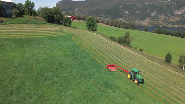 Pull-type Forage Harvester Cutting Green Grass On Field For Silage Production. - aerial alt