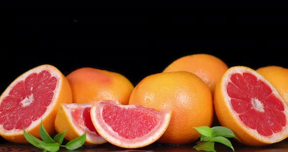 The Slices and Whole Grapefruits with Leaves Falling Drops of Water.  alt
