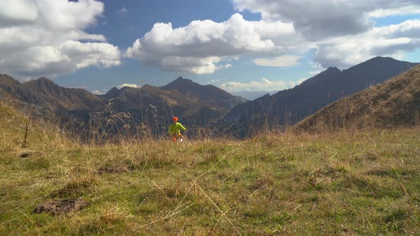 Two Mountain Biker Cycling up Pasture in Mountains