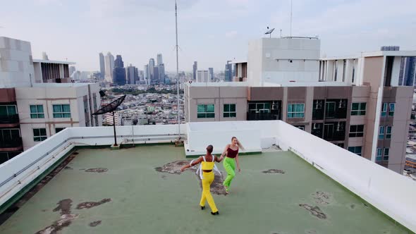 Drone Shot Of Models In Green And Yellow Dancing On City Rooftop alt