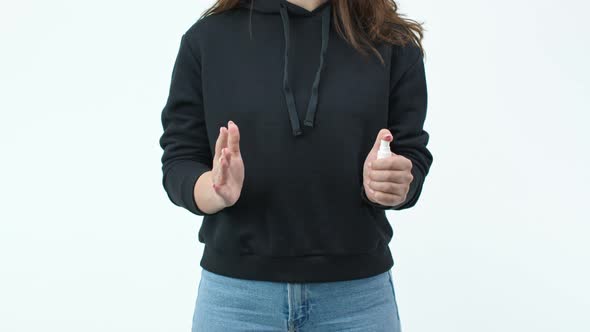 Caucasian Girl in Black Sweatshirt and Jeans Disinfects Hands with an Antiseptic alt