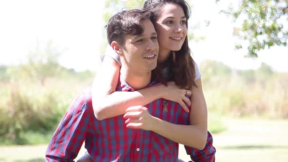 Young man giving his girlfriend a piggyback ride outdoors
