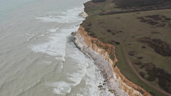 Drone shot of eroding white chalk cliffs turning brown England coast alt