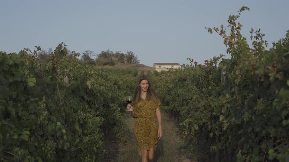 A Woman Walks Through a Vineyard with a Glass of Wine