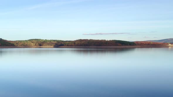 Drone aerial view of a lake reservoir of a dam with perfect reflection on the water of the sunset in alt