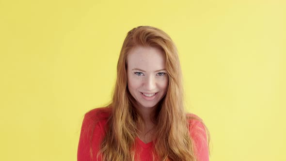 woman with red hair looks into camera on an isolated yellow background