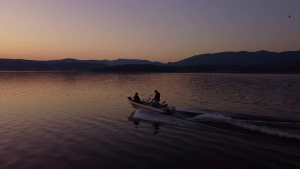 Aerial View of a Fishermens on a Speed Motor Boat Fishing on a Lake with Beautiful Sunrise alt