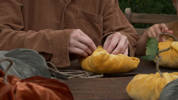 Woman make handmade pumpkins made of fabric on wooden table