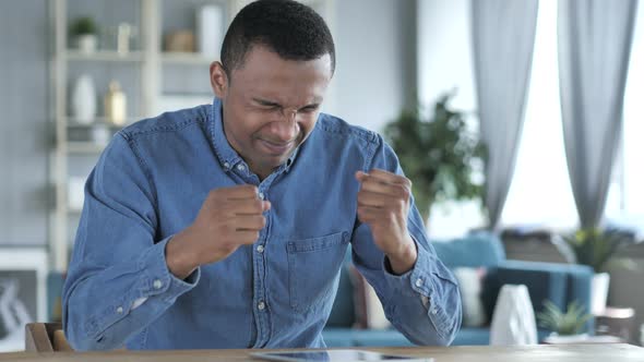 Young African Man Upset for Loss while Using Tablet alt