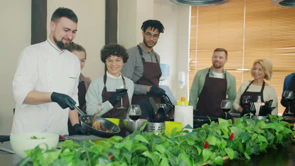 Slow Motion of Young Man Chef Frying Food Cooking Meal Teaching Group of Trainees alt