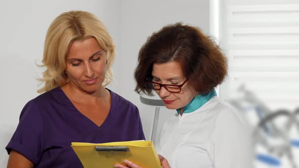 Female Doctors Examining Medical Survey Documents at the Clinic alt