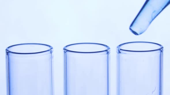 Pipette Drips Transparent Blue Chemicals Into a Three Test Tubes. Chemical and Medicine Concept alt