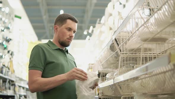 Bearded Man is Choosing Lamp in a Building Material Stores Unpacking It alt