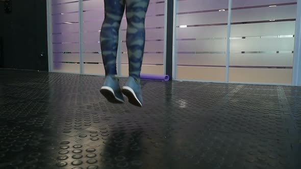 Slender energetic fitness girl jumping a skipping rope in fitness wellness club.