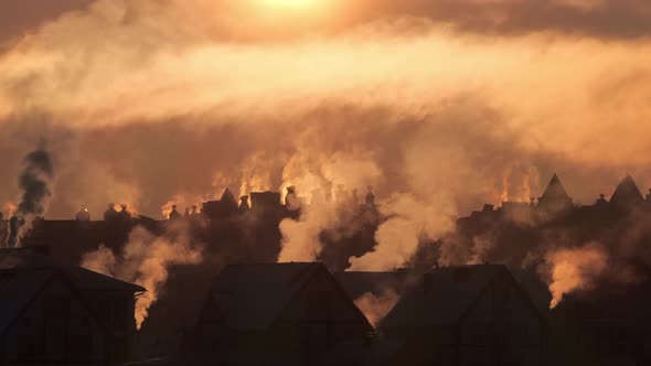 Smoke Rising From the Chimneys on Roofs in the Light of Sunset in Misty Winter