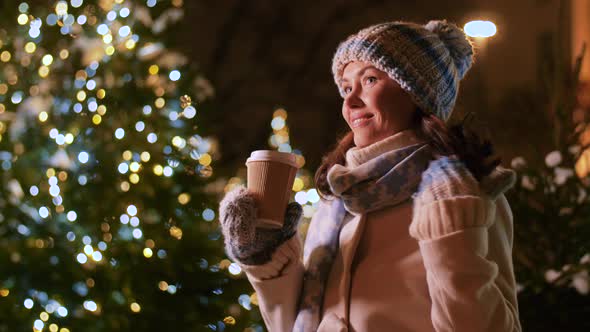 Happy Woman Drinking Coffee Over Christmas Lights alt