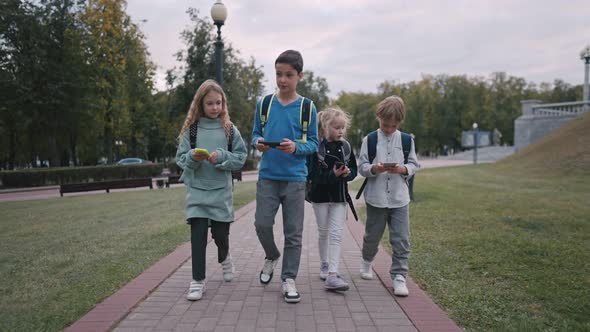 Long Shot of Four Pupils with Backpacks Going Out of School and Talking alt