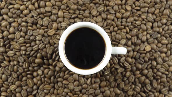 A Cup Of Black Coffee On A Background Of Rotating Coffee Beans.