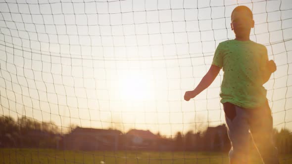The Boy Catches the Ball in the Football Goal alt