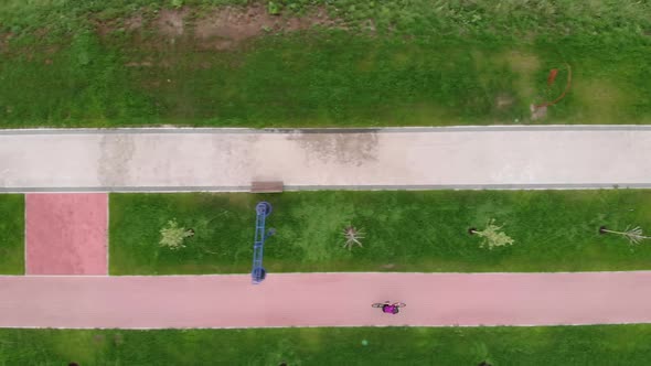 Drone shot of sportive female cycling on bike in summer. Happy cyclist woman rides on bike. alt