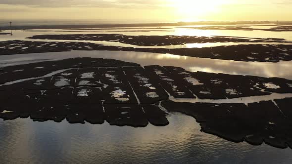 An aerial shot over Baldwin Bay near Freeport, NY at sunset. The camera dolly out from the sun as it alt