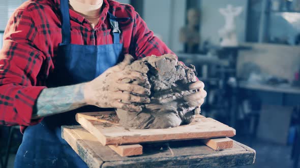 Male Sculptor is Taking a Piece of Clay and Starts Kneading It alt