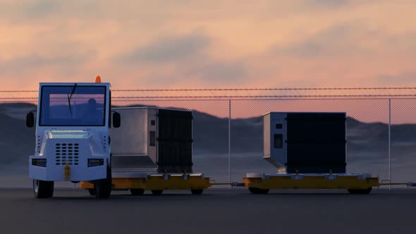 Transport of cargo containers at airport by a baggage tug during sunset. 4KHD