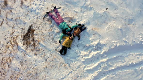 Top View of a Mother with Two Young Sons Making a Snow Angel