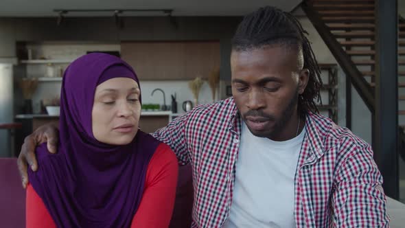 Attractive Multiethnic Muslim Couple Talking and Bonding on Sofa in Domestic Room alt