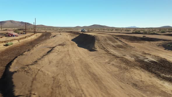 Flying over a dirt motocross racetrack as a water truck sprays the dirt surface alt