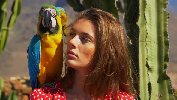 Macaw Parrot Perching on Models Shoulder with Cacti in the Background alt