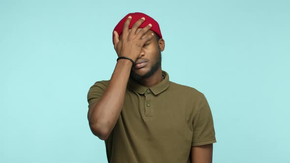 Disappointed African American Man in Red Beanie Making Facepalm Gesture Shaking Head Upset and Tired