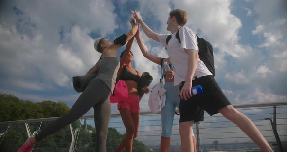 Young People Give High Five to Each Other Smiling Under Sky alt