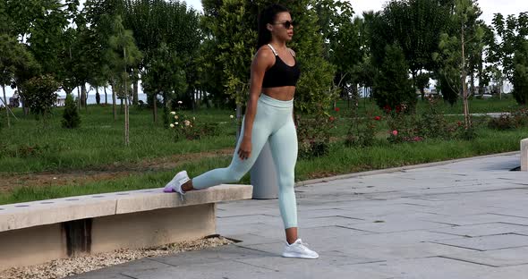 Young fit sporty black African woman in top and leggings does leaning forward exercise.