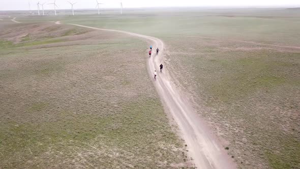 A Group of Cyclists Rides Along the Windmills alt