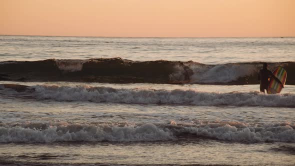 Surfers On Slow Motion Sea At Sunset alt
