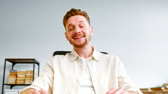 Joyful financial director with beard waves hand and talks smiling with co workers alt