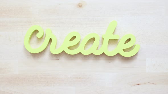 Green create sign with paint brushes on the table. alt