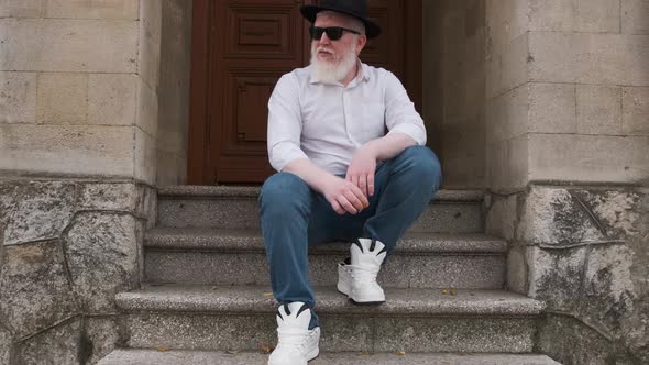 Man Suffering From Albinism Sits Outside Smokes a Cigarette.. alt