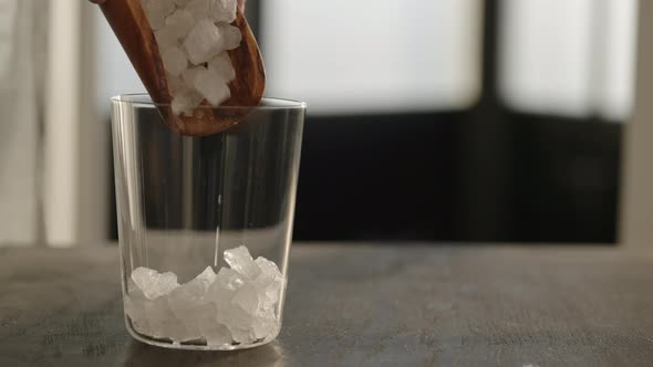 Slow Motion Fill Tumbler Glass with Crushed Ice on Oak Table with Copy Space alt