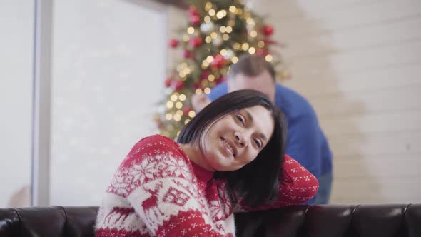 Loving Daughter and Husband Hugging Smiling Beautiful Woman Sitting on Couch with Decorated alt