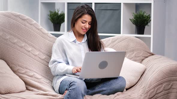 Feminine Typing Use Computer Sitting on Comfortable Sofa alt