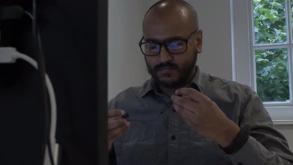 Male Office Worker Walking To Desk And Sitting Down, Inserting Earphones. Locked Off, Establishing S alt