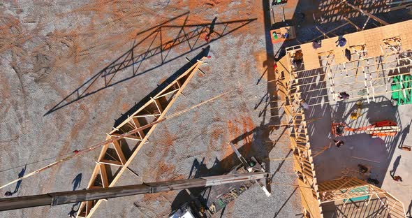 Aerial View of Wooden Roof with Crane Holds a Roof Truss Beams for Installing alt