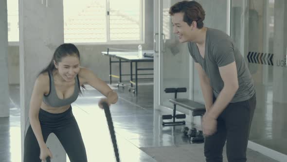 Young asian woman strong doing battle rope exercise in the gym. alt
