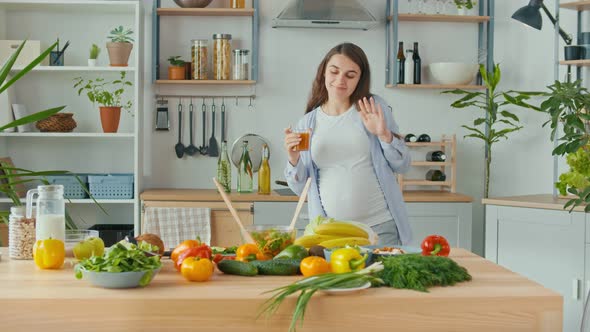 Happy Pregnant Woman Drinks Vegetable Fruit Juice in the Kitchen alt
