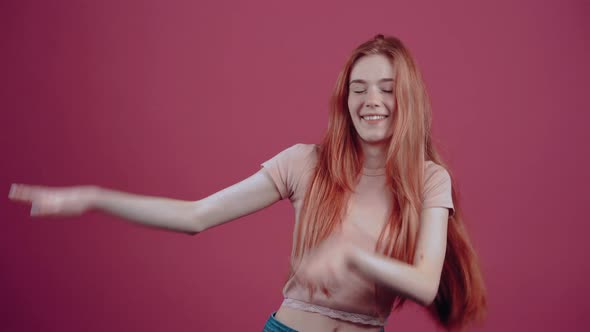 The 20Yearold Redhead Vesela is Having Fun in a Pink Casual Tshirt Isolated on a Pink Background alt